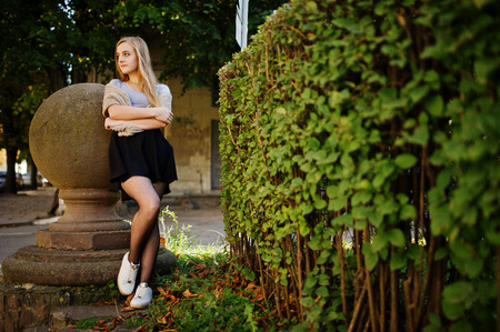 Young blonde girl in black skirt with scarf posed at street of city.の写真素材