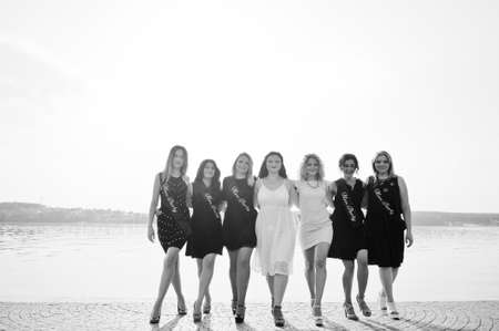 Group of 7 girls wear on black and 2 brides at hen party against sunny beach.の写真素材