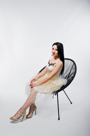Portrait of brunette girl on beige dress with chair isolated on white.の写真素材