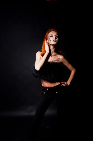Fashion model red haired girl with originally make up like leopard predator isolated on black. Studio portrait.の写真素材