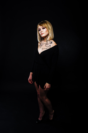 Studio portrait of blonde girl with originally make up on neck, wear on black dress at dark background.の写真素材