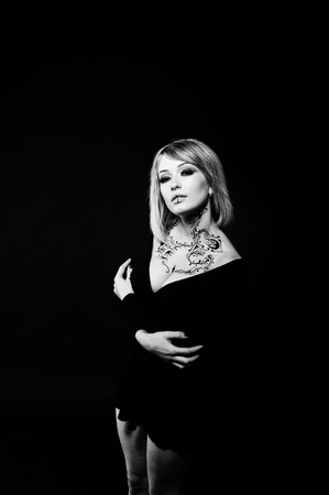 Studio portrait of blonde girl with originally make up on neck, wear on black dress at dark background.の写真素材