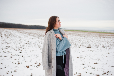 Gentle girl in gray coat against snow landscape.の写真素材