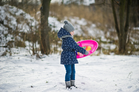 Cute little girl with saucer sleds outdoors on winter day.の写真素材
