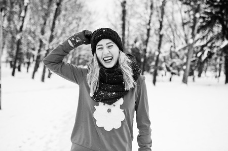 Blonde girl in red scarf, hat and santas sweater posing at park on winter day.の写真素材