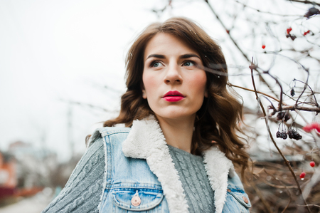 Portrait of brunette girl in jeans jacket at frozen bushes.の写真素材