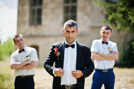 Groom posing with two groomsmen on a sunny wedding day next to the castle.の写真素材