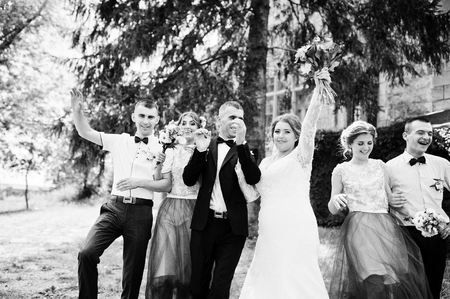 Bridesmaids with groomsmen and wedding couple jumping, dancing and having fun next to an old building. Black and white photo.の写真素材