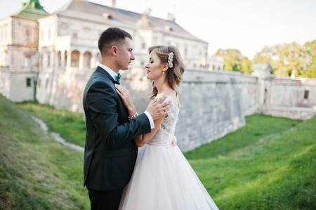 Fabulous wedding couple posing in front of an old medieval castle in the countryside on a sunny day.の写真素材