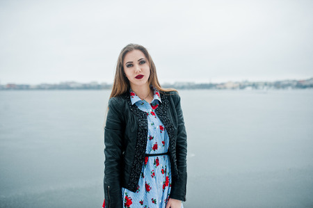 Stylish girl in leather jacket at winter day against frozen lake.