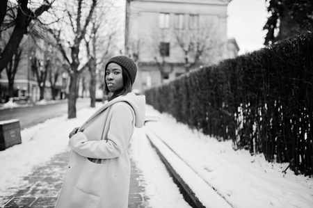 African american girl in red hat and pink coat at street of city on winter day.の写真素材