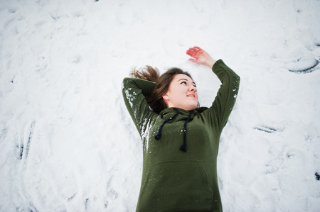 Funny girl wear on long green sweatshirt and jeans, at frozen lake in winter day.