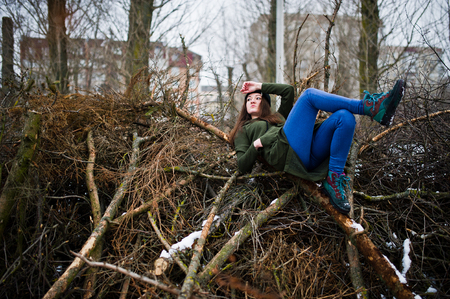 Young girl wear on long green sweatshirt, jeans and black headwear at  branches of the pine tree in winter day.の写真素材