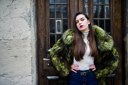 Brunette girl in green fur coat against old wooden doors.の写真素材