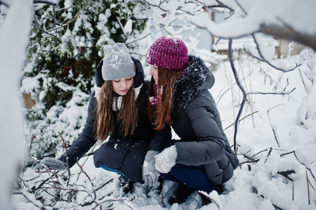 Two funny girls friends having fun at winter snowy day near snow covered trees.の写真素材
