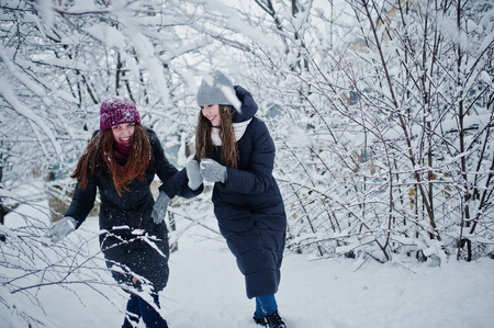 Two funny girls friends having fun at winter snowy day near snow covered trees.の写真素材