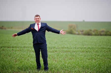 Portrait of a happy groom standing in the middle of green field on the wedding day.の写真素材