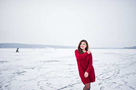 Brunette plus size model at red against frozen lake on winter day.の写真素材