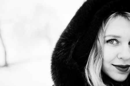 Elegance blonde girl in fur coat and red evening dress posed at winter snowy day.の写真素材