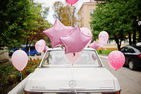 Hai, Ukraine - 07 November,2017: white retro Mercedes-Benz W114 with pink balloons riding on th streets of the town.のeditorial素材