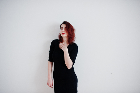Red haired girl on black dress tunic against white wall at empty room.の写真素材