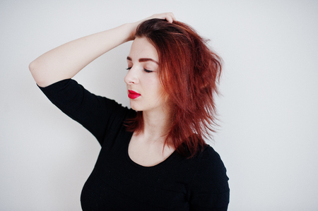 Red haired girl on black dress tunic against white wall at empty room.の写真素材