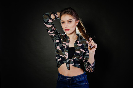 Handsome brunette girl wear military shirt and jeans, posing at studio against gray background. Studio model portrait.の写真素材