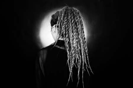 Studio shoot back of girl in black with dreads at black background with nimbus.