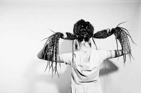 Studio shoot back of girl in gray dress with pigtails dreads on white background.の写真素材