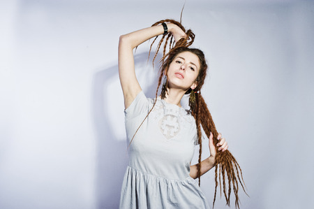 Studio shoot of girl in gray dress with dreads pigtails on white background.