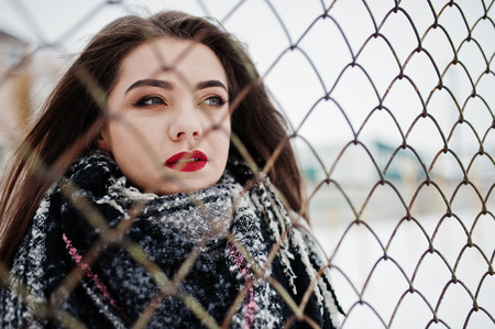 Close up portrait of brunette girl in scarf against cage.の写真素材
