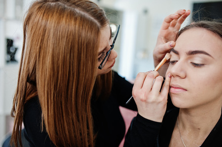 Make up artist work in her beauty visage studio salon. Woman applying by professional make up master. Beauty club concept.の写真素材