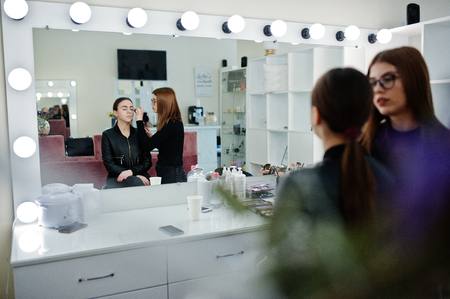 Make up artist work in her beauty visage studio salon. Woman applying by professional make up master. Beauty club concept.の写真素材