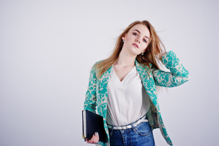 Stylish blonde girl in jacket and jeans with notebook diary at hands against white background on studio.の写真素材