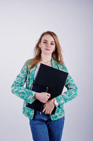 Stylish blonde girl in jacket and jeans with notebook diary and laptop at hands against white background on studio.の写真素材