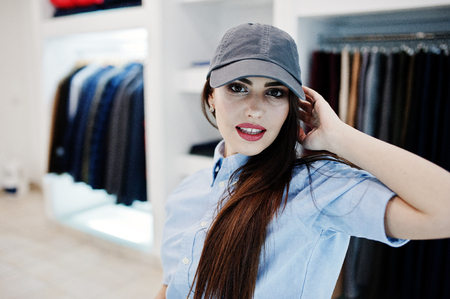 Brunette gorgeous girl in the clothing store boutique at casual clothes and cap.の写真素材