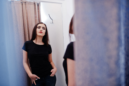 Brunette gorgeous girl in the clothing store boutique at casual clothes, black shirt and jeans.の写真素材