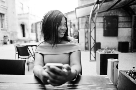 African american woman model xxl in orange dress looking on mobile phone.の写真素材