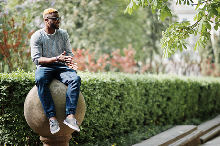 Stylish african american boy on gray sweater and black sunglasses posed on street. Fashionable black guy.の写真素材