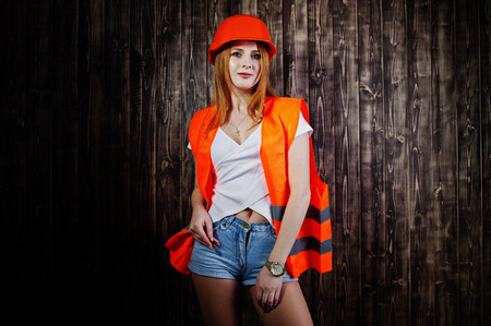 Engineer woman in orange protect helmet and building jacket against wooden background.の写真素材