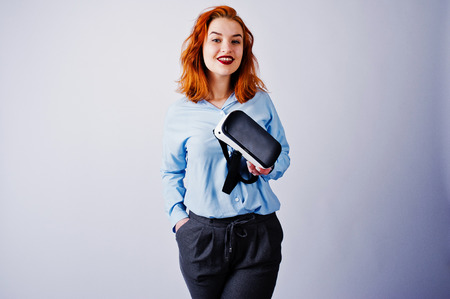 Red haired girl in blue blouse with vr glasses at studio isolated on white.の写真素材