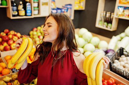 Girl in red holding bananas on fruits store.の写真素材