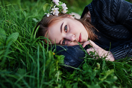 Young brunette girl lying on green grass with branches of blossom tree.の写真素材
