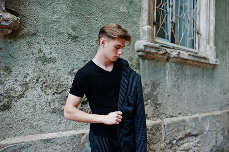 Young stylish macho boy in black jacket posed outdoor of street. Amazing model man.の写真素材