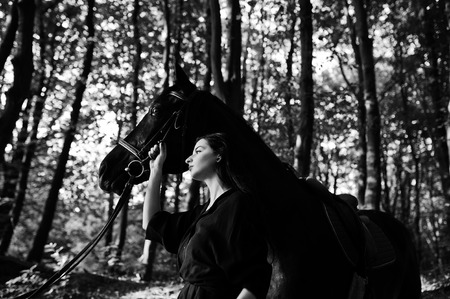 Mystical girl wear in black with horse in wood.の写真素材