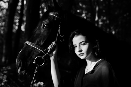 Mystical girl wear in black with horse in wood.の写真素材
