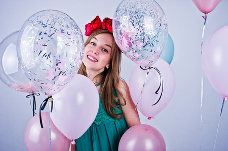Happy girl in green turqoise dress and wreath with colored balloons isolated on white. Celebrating birthday theme.の写真素材