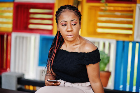 Stylish african american woman posed outdoor and using mobile phone.