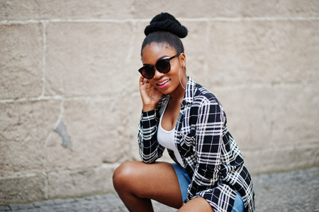 Hip hop african american girl on sunglasses and jeans shorts. Casual street fashion portrait of black woman.の写真素材