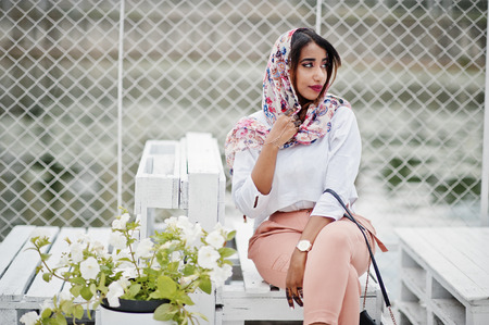 Fashion arabian girl at white blouse and peach pants posed outdoor. Stylish muslim woman.